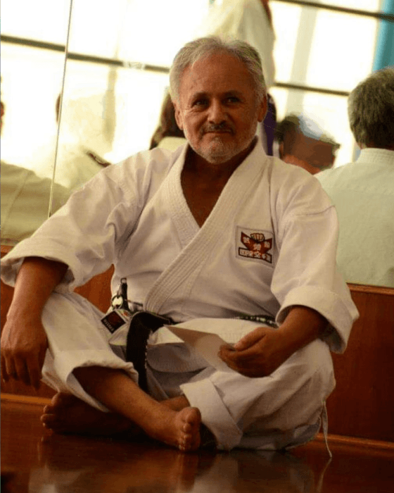 Shihan Dai Juan Pastén sentado en el dojo con gi blanco y cinturón negro